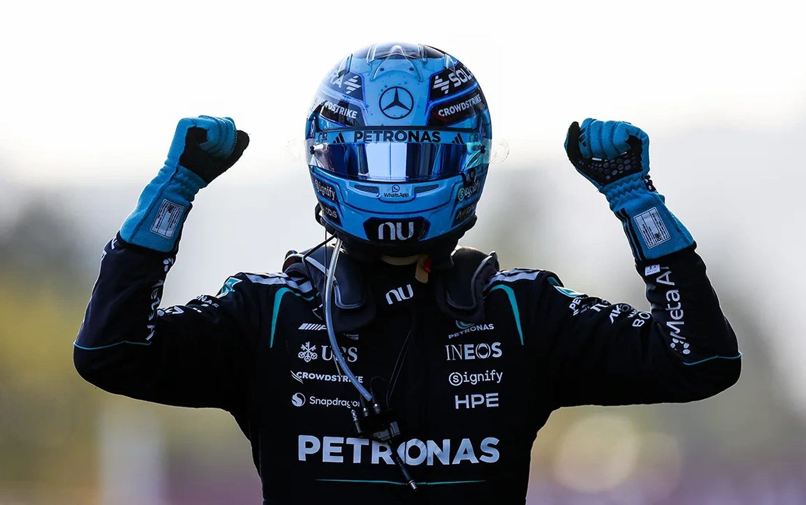 George Russell celebrates his 2026 Azerbaijan Grand Prix victory in Mercedes racewear and helmet.